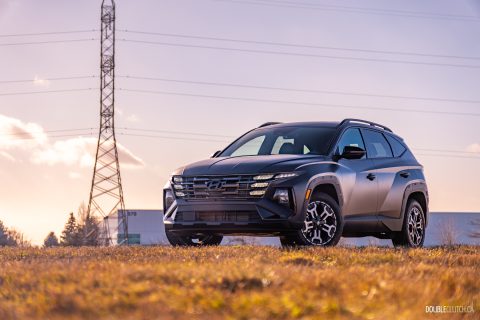 Front three quarter view of 2025 Hyundai Tucson XRT in matte grey at sunset on grass