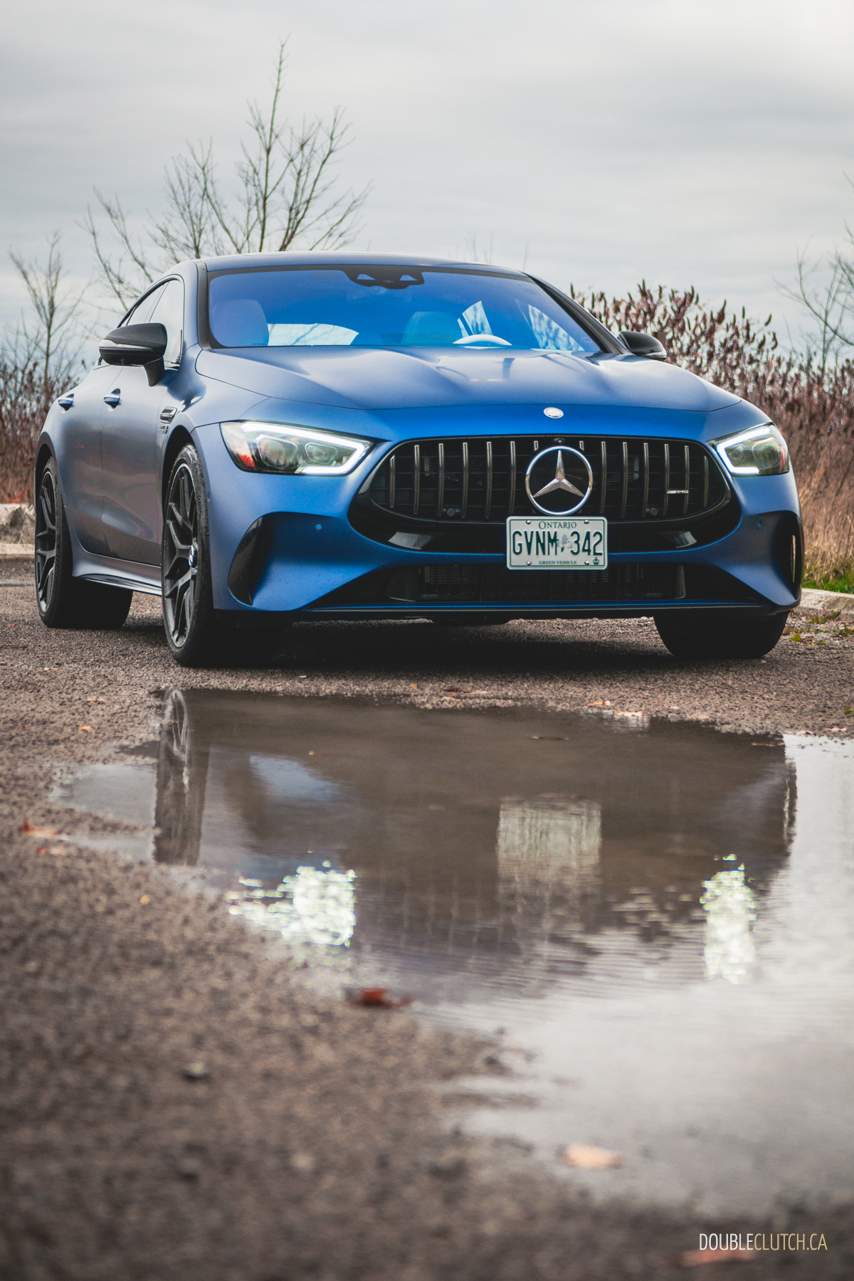 2025 Mercedes-AMG GT 63 S E-Performance 4-Door Coupe front three quarter view on cloudy day with reflection over water