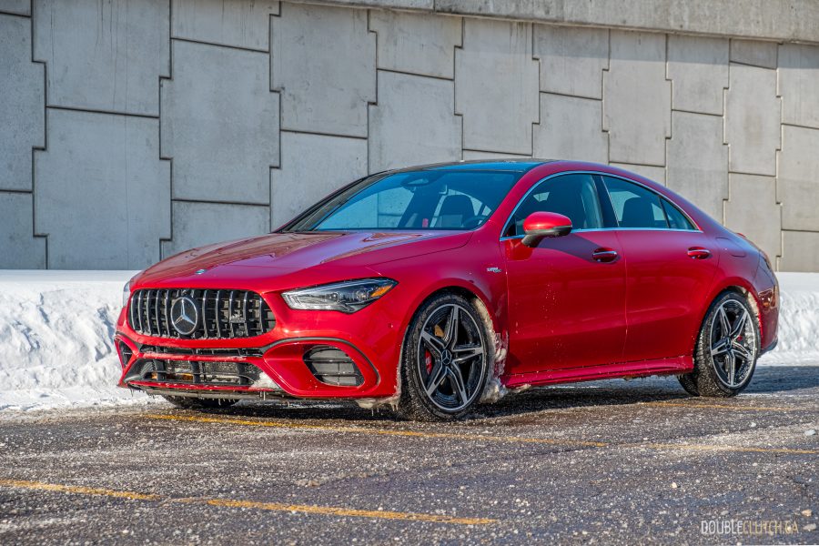 Front quarter view of a red 2025 Mercedes-AMG CLA 45 S parked beside a grey wall, with snow on the ground