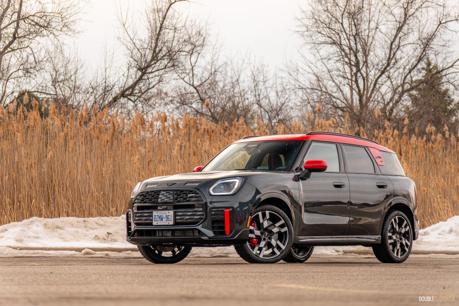 Front quarter view of a 2025 Mini Countryman JCW in a parking lot with trees and shrubs in the background