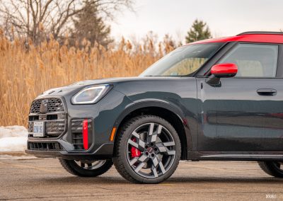 Front quarter view of a 2025 Mini Countryman JCW in a parking lot with trees and shrubs in the background
