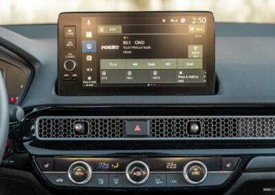 Close-up showing the infotainment display, air vent design, and climate control switchgear in a 2025 Honda Civic Hybrid Hatchback