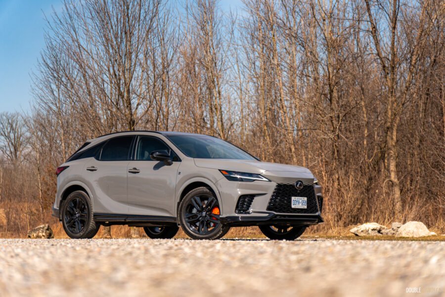 Front quarter view of a grey 2025 Lexus RX 500h Black Line Special Edition on a sunny day with trees in the background