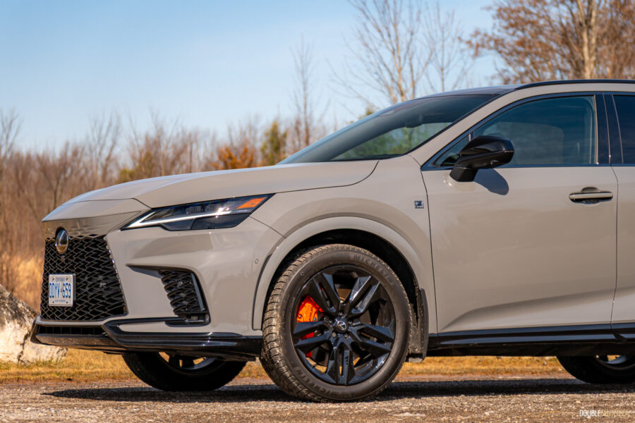 Front quarter view of a grey 2025 Lexus RX 500h Black Line Special Edition on a sunny day with trees in the background