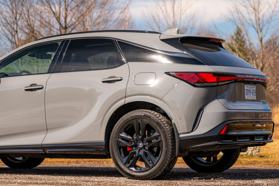 Rear quarter view of a grey 2025 Lexus RX 500h Black Line Special Edition on a sunny day with trees in the background