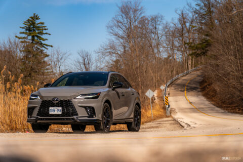 Front quarter view of a grey 2025 Lexus RX 500h Black Line Special Edition on a sunny day with trees in the background