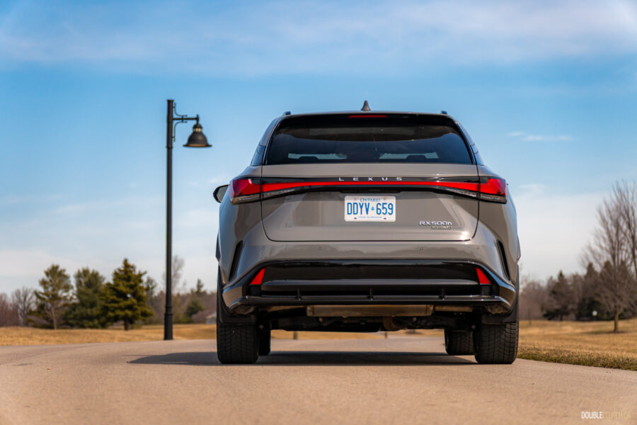 Rear view of a grey 2025 Lexus RX 500h Black Line Special Edition on a sunny day with trees in the background