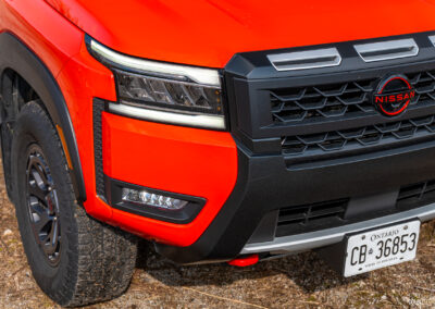 Close-up showing the restyled headlights, front grille, and bumper on a 2025 Nissan Frontier PRO-4X Luxury