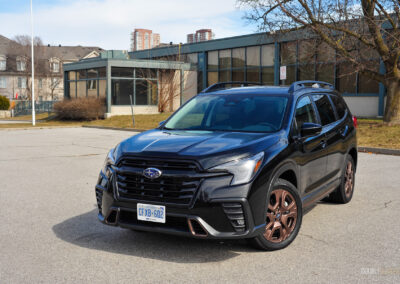 Front quarter view of a black 2025 Subaru Ascent on a sunny day, with houses in the background
