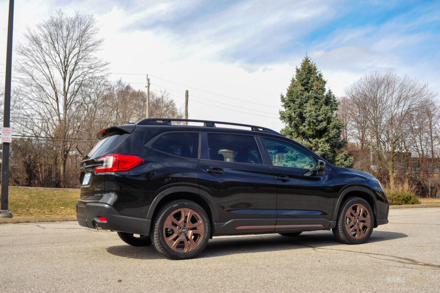 Rear quarter view of a black 2025 Subaru Ascent on a sunny day, with trees in the background