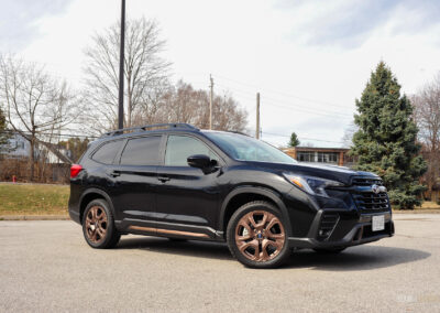 Front quarter view of a black 2025 Subaru Ascent on a sunny day, with trees in the background