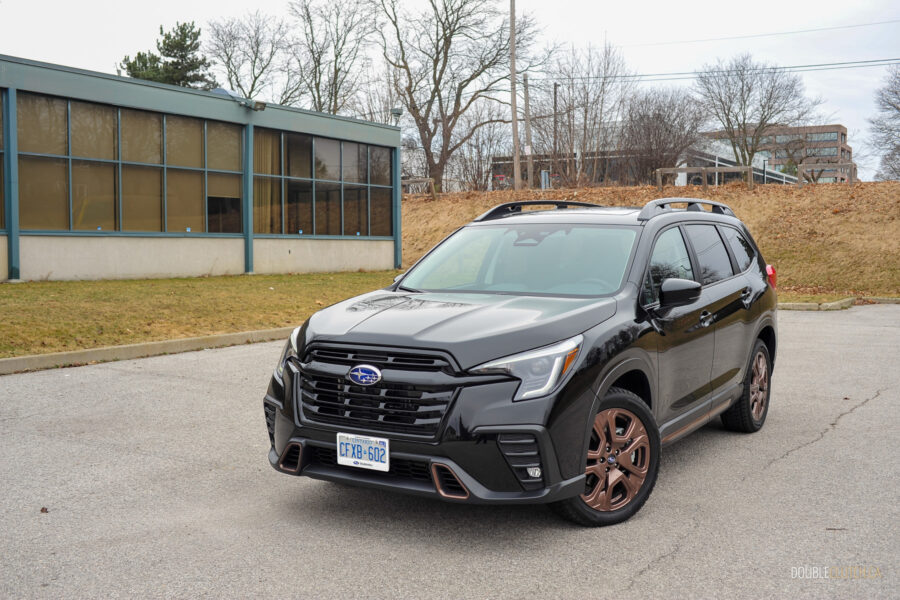 Front quarter view of a black 2025 Subaru Ascent on a cloudy day, with trees and houses in the background