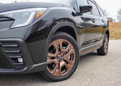 Front quarter close-up view of a black 2025 Subaru Ascent showing the blacked-out trim and bronze wheels