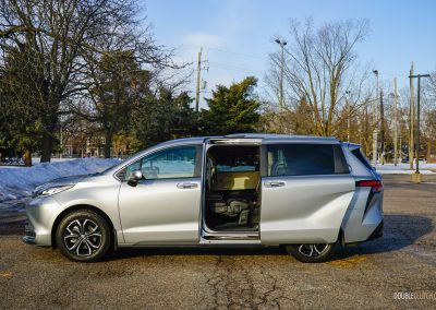 Side profile view of a 2025 Toyota Sienna with the door open against a backdrop of trees