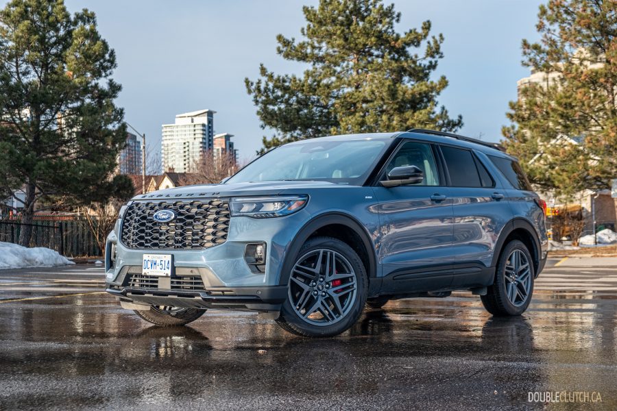 Front quarter view of the 2025 Ford Explorer ST-Line parked over a puddle, with snow on the ground and trees in the background
