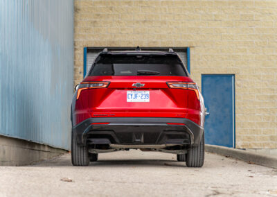 Rear view of a red 2025 Chevrolet Equinox RS with a building in the background