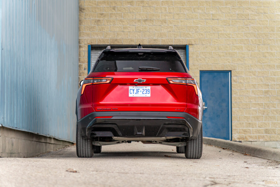 Rear view of a red 2025 Chevrolet Equinox RS with a building in the background