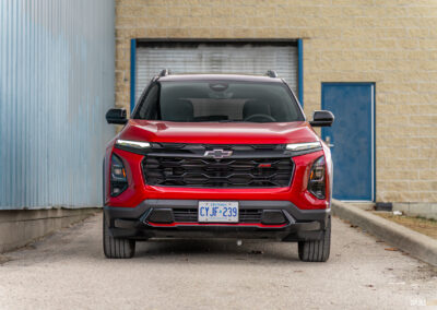 Front view of a red 2025 Chevrolet Equinox RS with a building in the background