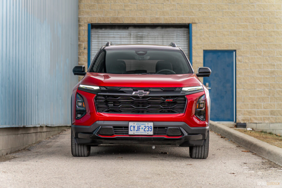 Front view of a red 2025 Chevrolet Equinox RS with a building in the background