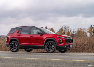 Front quarter view of a red 2025 Chevrolet Equinox RS on a cloudy day with trees in the background
