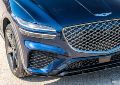 Close-up showing the headlight, grille, and front fascia design on a 2025 Genesis GV70 3.5T Sport Plus