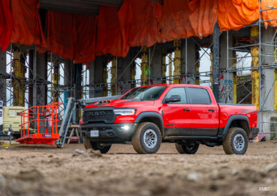 Front quarter view of a red 2025 Ram 1500 RHO, parked in a muddy construction site