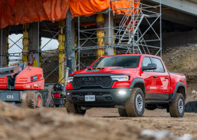 Front quarter view of a red 2025 Ram 1500 RHO, parked in a muddy construction site
