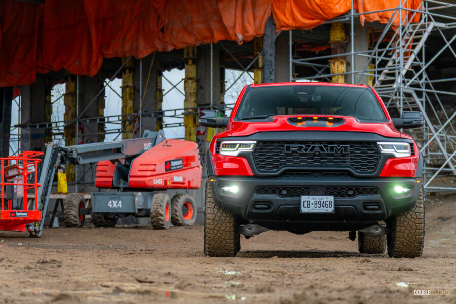 Front view of a red 2025 Ram 1500 RHO, parked in a muddy construction site