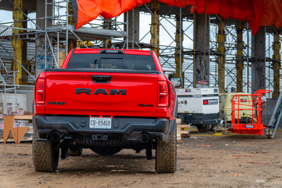 Rear view of a red 2025 Ram 1500 RHO, parked in a muddy construction site