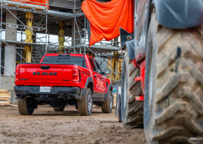 Rear quarter view of a red 2025 Ram 1500 RHO, parked in a muddy construction site