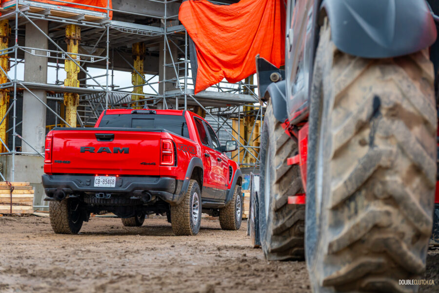 Rear quarter view of a red 2025 Ram 1500 RHO, parked in a muddy construction site