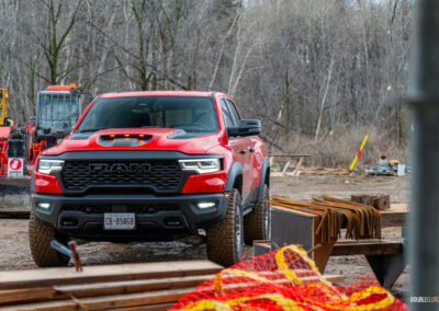 Front quarter view of a red 2025 Ram 1500 RHO, parked in a muddy construction site