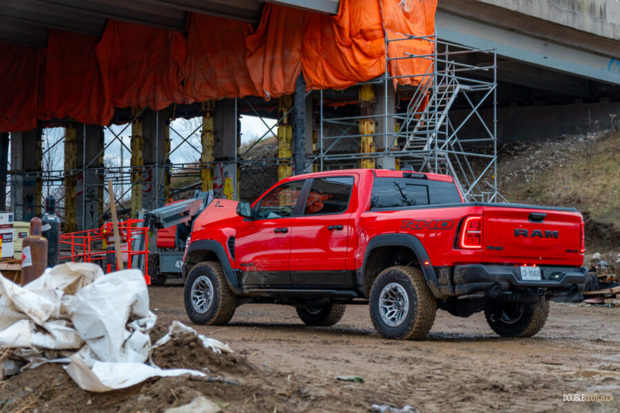 Rear quarter view of a red 2025 Ram 1500 RHO, parked in a muddy construction site