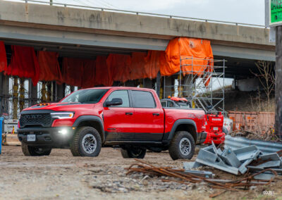 Front quarter view of a red 2025 Ram 1500 RHO, parked in a muddy construction site