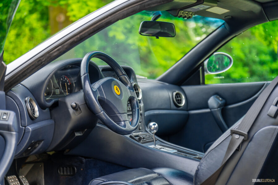 The blue interior of a 1996 Ferrari 550 Maranello, from the outside looking in at the cockpit