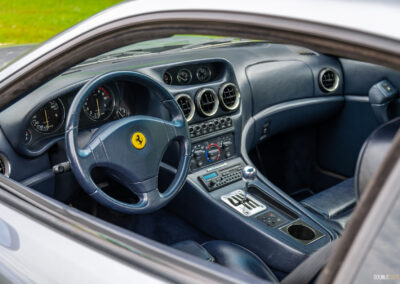 The blue interior of a 1996 Ferrari 550 Maranello, from the outside looking in at the cockpit through the driver's side door