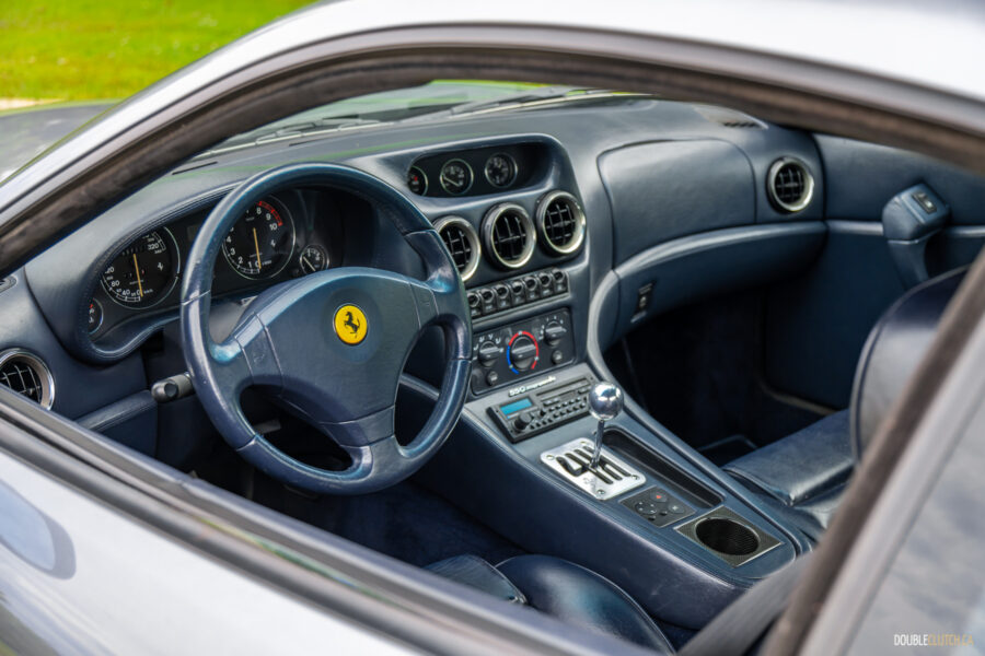 The blue interior of a 1996 Ferrari 550 Maranello, from the outside looking in at the cockpit through the driver's side door