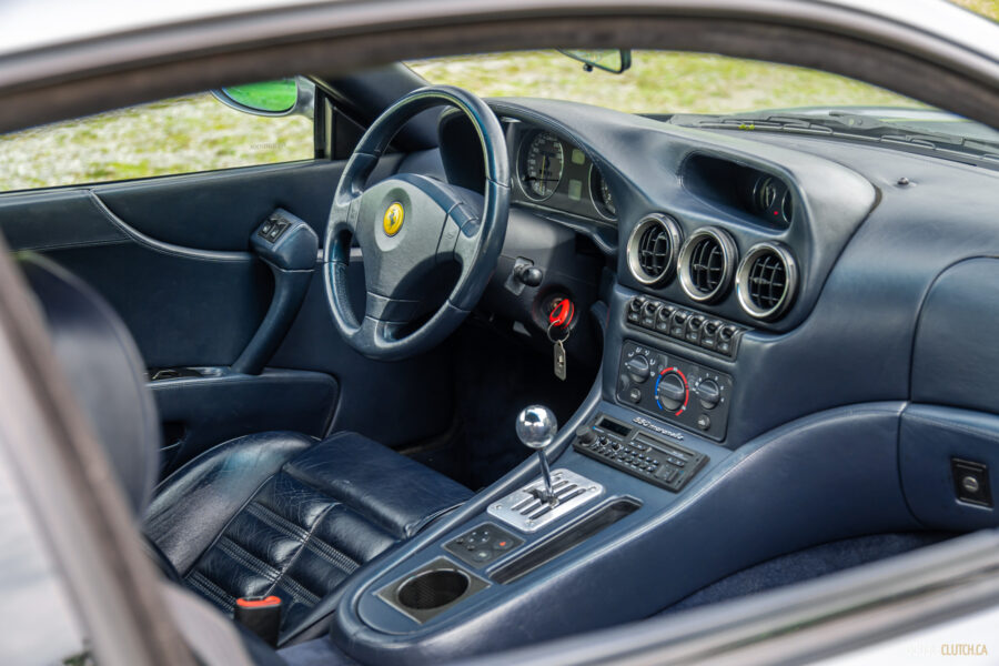 The blue interior of a 1996 Ferrari 550 Maranello, from the outside looking in at the cockpit through the driver's side door
