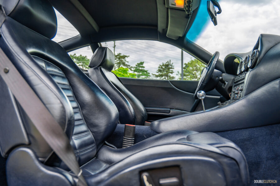 The blue interior of a 1996 Ferrari 550 Maranello, from the outside looking in at the front passenger seat