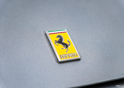 Close-up of the Ferrari badge on the hood of a grey 1996 Ferrari 550 Maranello