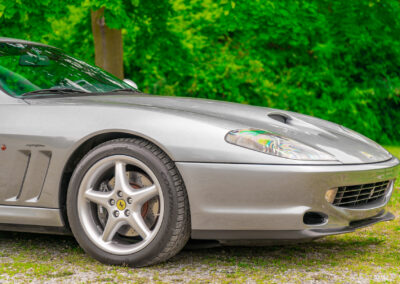 Cropped front quarter view showing the long hood of a grey 1996 Ferrari 550 Maranello