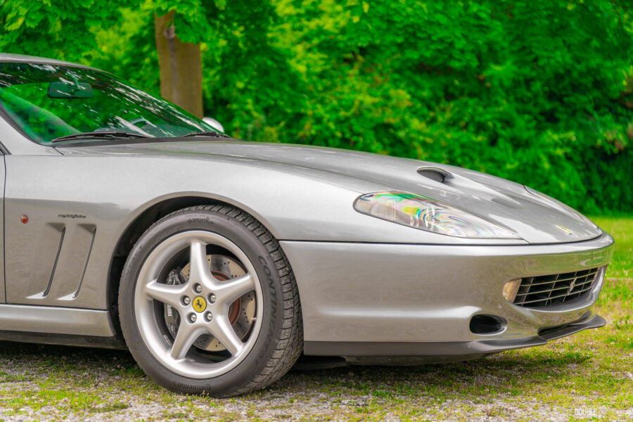 Cropped front quarter view showing the long hood of a grey 1996 Ferrari 550 Maranello