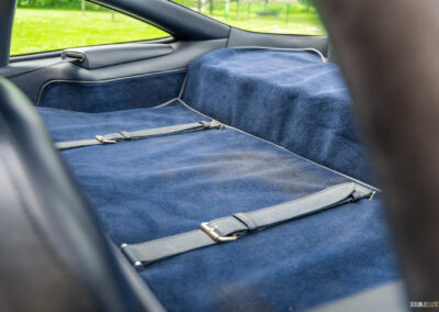 Close-up of the carpeted storage bench behind the front seats of a 1996 Ferrari 550 Maranello