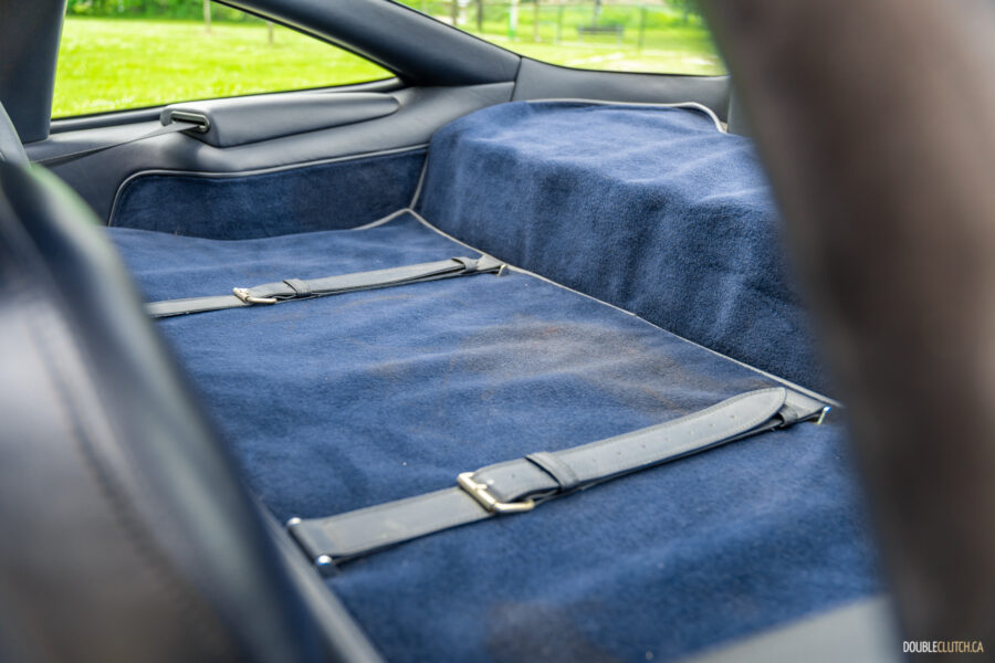 Close-up of the carpeted storage bench behind the front seats of a 1996 Ferrari 550 Maranello