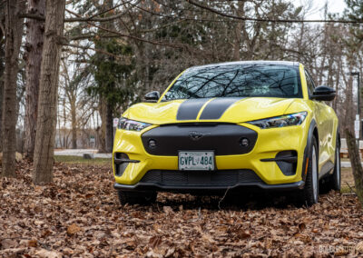 Front view of a yellow 2025 Ford Mustang Mach-E Rally in a forest