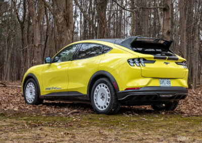 Rear quarter view of a yellow 2025 Ford Mustang Mach-E Rally in a forest