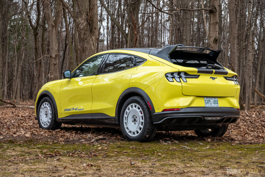Rear quarter view of a yellow 2025 Ford Mustang Mach-E Rally in a forest
