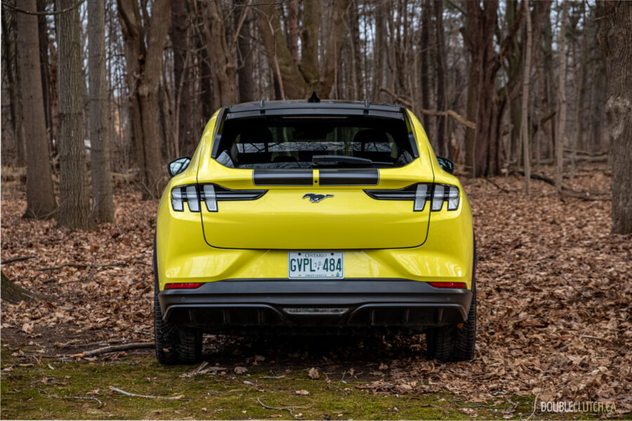 Rear view of a yellow 2025 Ford Mustang Mach-E Rally in a forest