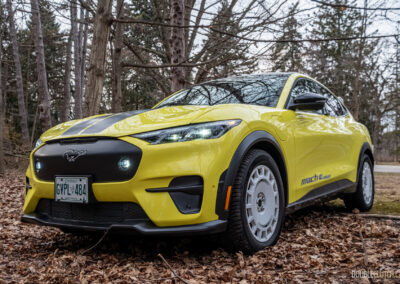Front quarter view of a yellow 2025 Ford Mustang Mach-E Rally in a forest