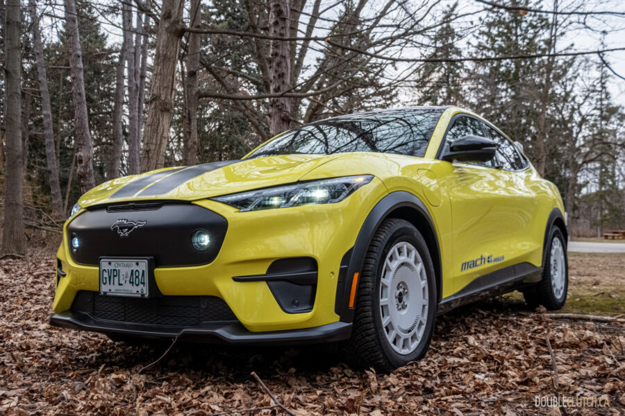 Front quarter view of a yellow 2025 Ford Mustang Mach-E Rally in a forest